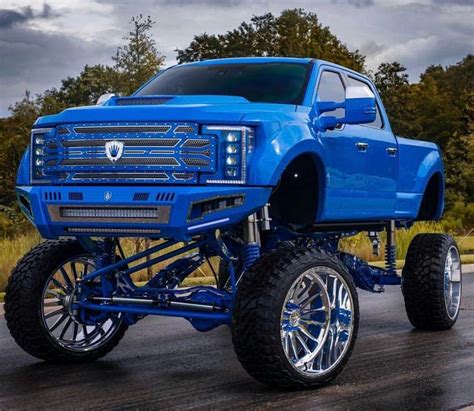 A Blue Truck With Big Tires On The Road