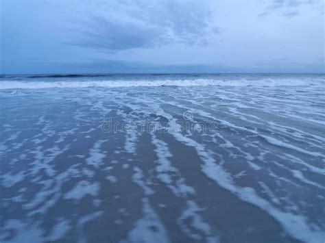 Beautiful Shot Of Foamy Waves Covering A Sandy Beach Stock Photo