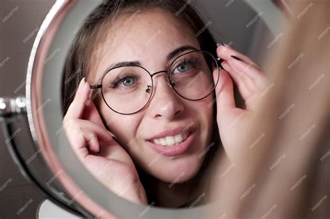 Premium Photo Beautiful Girl Tries On Glasses While Admiring Herself
