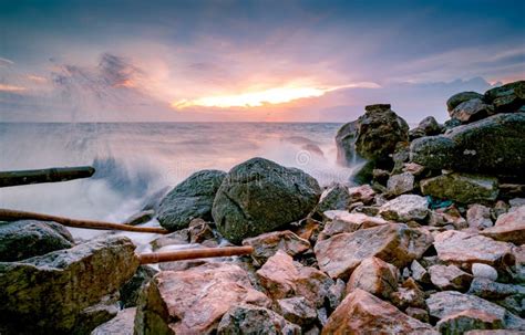 Ocean Water Splash On Rock Beach With Beautiful Sunset Sky And Clouds