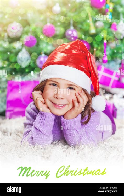 Little Girl Lying Down Near Christmas Tree At Home Little Santa Helper