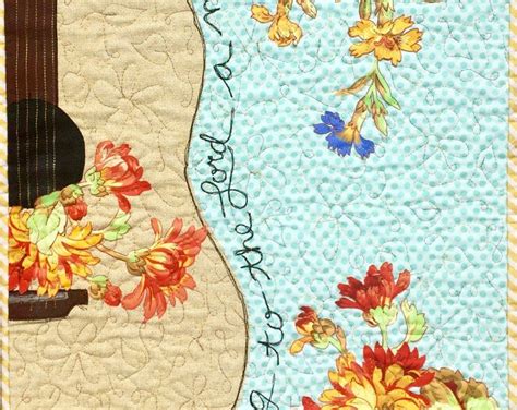 A Quilted Wall Hanging With An Acoustic Guitar And Flowers On The Front