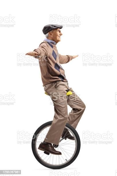 Full Length Profile Shot Of An Elderly Man Riding A Monocycle And