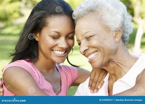 African American Mother And Adult Daughter Relaxing In Park Stock Image