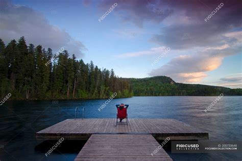 Woman Relaxes And Watches The Sunset From The Wharf At Gardom Lake Near
