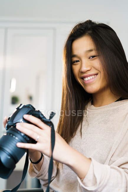 Young Chinese Woman Looking At The Camera Smiling And Holding A Camera