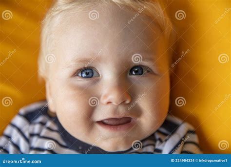 Close Up Of A Cute 9 Month Old Baby Boy With Blue Eyes On A Yellow