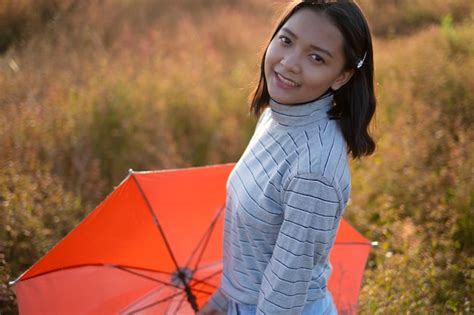 Premium Photo Young Asian Girl Hold Orange Umbrella And Smiling At