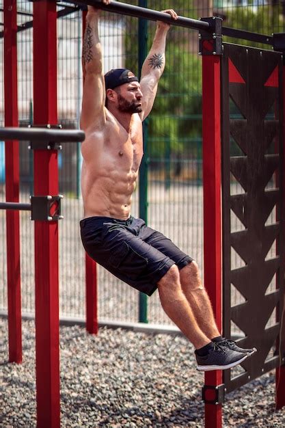 premium photo strong muscular bearded man doing abdominal exercise on horizontal bar in summer