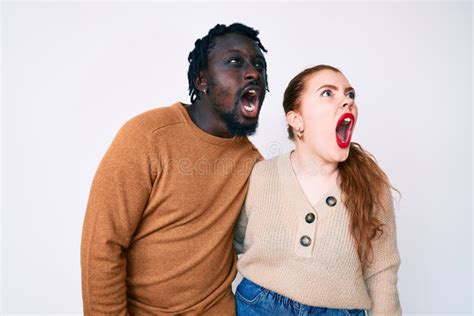 interracial couple wearing casual clothes angry and mad screaming frustrated and furious
