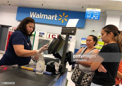 Customers Look On As A Walmart Cashier Rings Up Their Purchases At A