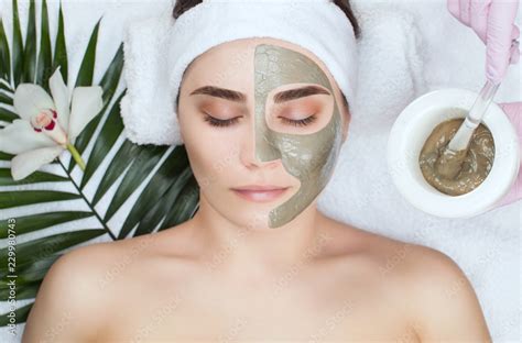 The Procedure For Applying A Mask From Clay To The Face Of A Beautiful Woman Spa Treatments And