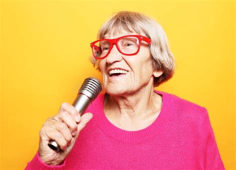 Happy Old Senior Woman Singing With Microphone Having Fun Expressing Musical Talent Stock