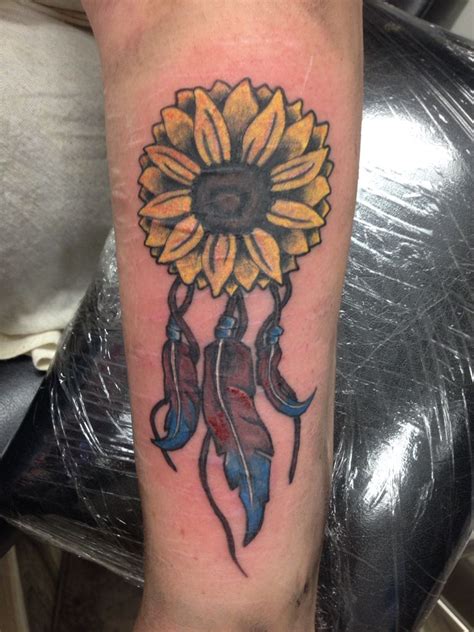 A Sunflower Tattoo On The Arm With Feathers