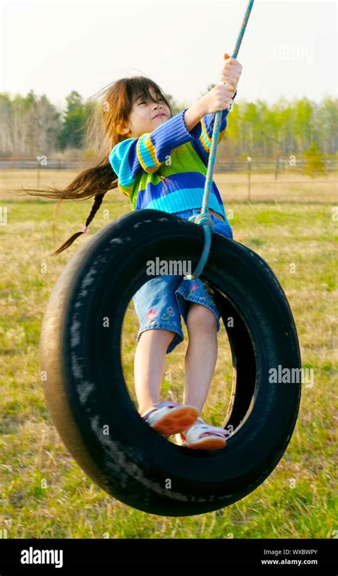 Little Girl Swinging On Tire Swing In The Countryside Stock Photo Alamy