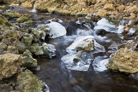 Blurred Water Flowing Down A Rocky Creek Through Ice Stock Image