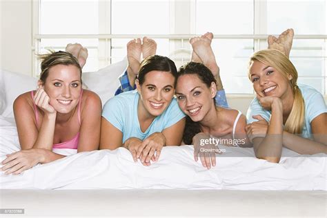 Portrait Of Four Young Women Lying Down Side By Side On A Bed Foto De