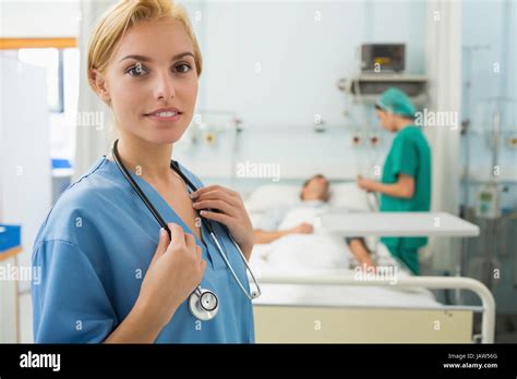 Blonde Nurse Smiling While Standing Up In Hospital Ward Stock Photo Alamy