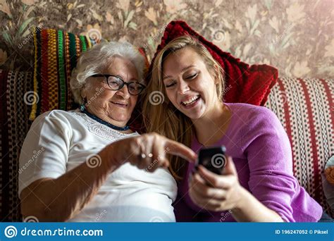 Senior Woman And Her Adult Granddaughter Using Smartphone Together