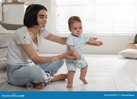 madre apoyando a su hija pequeña mientras aprende a caminar en casa imagen de archivo imagen