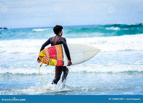 Surfer Guy With Surfboard In Hand Running Towards Big Waves Stock Photo