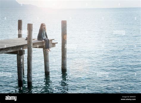 Woman Sitting On Pier Looking Away Stock Photo Alamy