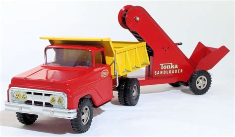 A Red And Yellow Toy Truck With A Dumpster Attached To Its Back