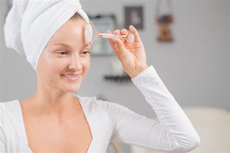 massage facial une belle femme se fait masser le visage en utilisant un rouleau facial jade pour