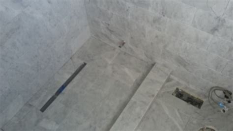 Dampen a sponge and wipe down the tumbled marble tile. White Carrara marble grout