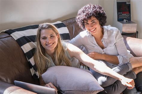 Caucasian Lesbian Couple Smiling On Sofa License Image 71071643