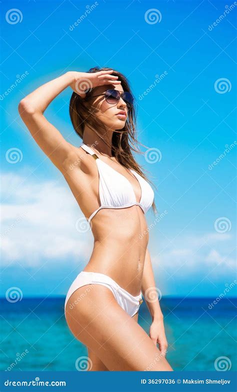 eine junge brunettefrau in einem weißen badeanzug auf dem strand stockfoto bild von