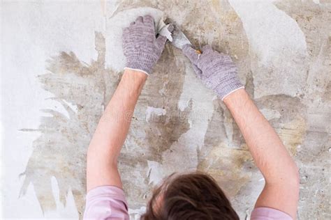 Caucasian Man Tearing Off Old Wallpaper From Wall Preparing For Home