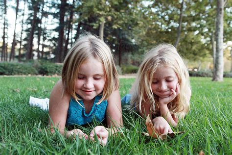 Young Blonde Sisters Laying On Grass By Dina Marie Giangregorio