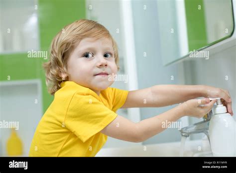 Little Kid Boy Washing His Hands With Soap In The Bathroom Stock Photo