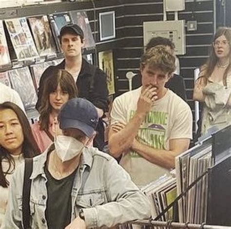 A Group Of People Standing Around In A Store With Masks On Their Faces