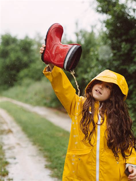 Playful Girl Pouring Rain Water From Boots By Stocksy Contributor