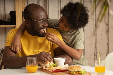 pai e filho comendo batatas fritas e hambúrgueres juntos foto premium