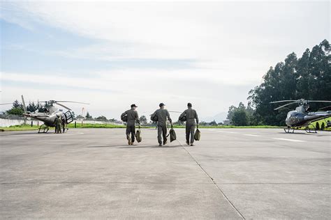 Three Military Men Walking On A Runway Towards The Helicopters