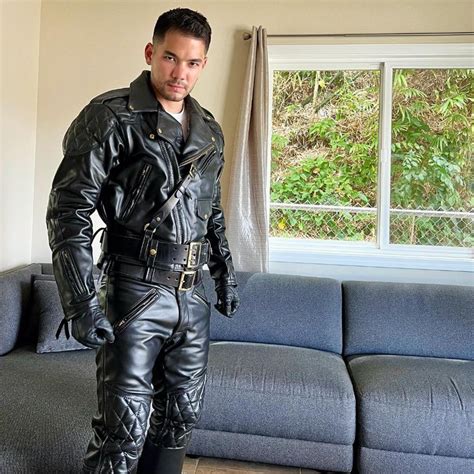 A Man In Black Leather Clothes Standing Next To A Couch