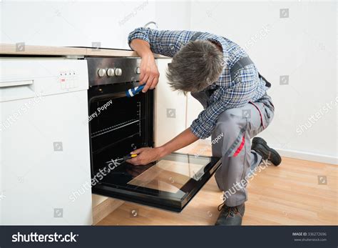 Full Length Repairman Examining Oven Flashlight Stock Photo 336272696