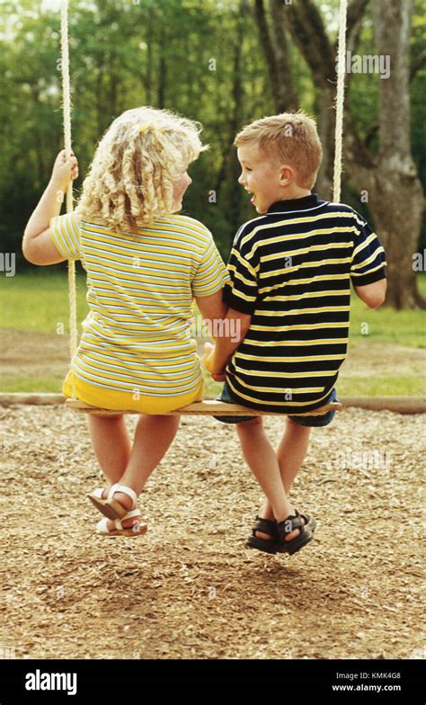 Boy And Girl On Swing Have Childhood Romance Stock Photo Alamy