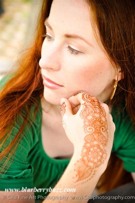 A Woman With Henna On Her Hand Looking Off To The Side And Holding Her Chin Up