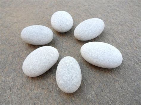 Five White Rocks Arranged In The Shape Of A Flower On Top Of A Gray Surface