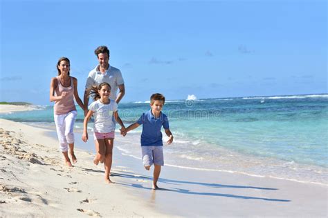 Familia Feliz Joven Que Corre En La Playa Que Se Divierte Imagen De