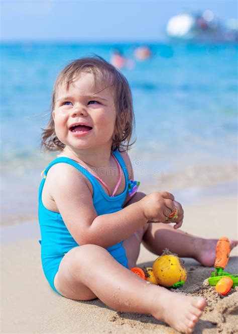 La Ragazza Del Bambino Sta Giocando Sulla Spiaggia Sabbiosa Vicino Al Mare Blu Immagine Stock