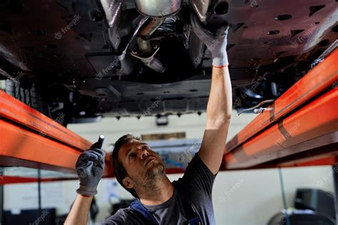 Free Photo Auto Repairman Examining Undercarriage Of A Car In A Workshop
