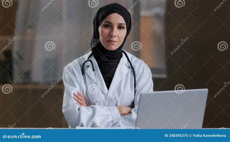 happy smiling arabian nurse islamic doctor therapist wear white uniform coat hijab sitting at