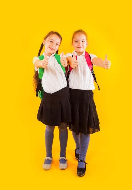 Premium Photo Two Friendly Schoolgirls In Uniform Are Holding Fingers Up