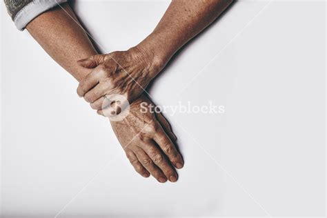 Top View Of An Elderly Womans Hands Resting On Grey Background
