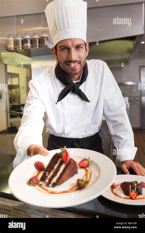 Happy Chef Offering Chocolate Cake To Camera In A Commercial Kitchen